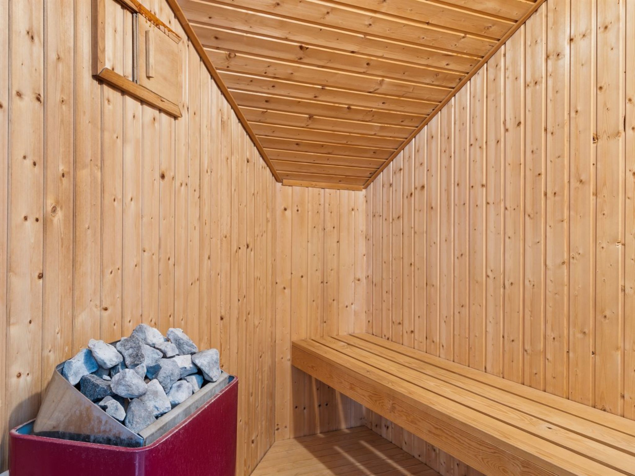A sauna with wooden walls and a sloped ceiling.