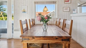 Une table à manger avec des chaises, un vase rempli de fleurs et une fenêtre donnant sur un immeuble.