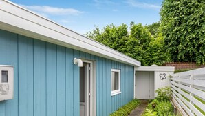 Ein blaues Gebäude mit einer weißen Tür, einem kleinen Fenster und einem weißen Zaun.