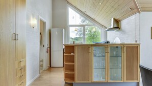 A modern kitchen with wooden cabinetry, a built-in refrigerator, and a large window providing natural light. - "Sigbritt" - 100m from the sea by Interhome (Broager)