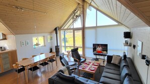 A spacious living area with a large sofa, dining table, and chairs. A television is mounted on the wall, and a fireplace is visible in the background. - "Sigbritt" - 100m from the sea by Interhome (Broager)