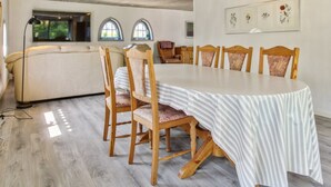 Ein Essbereich mit einem Holztisch und Stühlen, einer Couch und einem großen Fenster mit Rundbögen.
