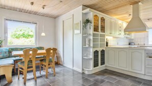 Eine moderne Küche mit Essbereich, ausgestattet mit Holzboden, grauen Fliesen und weißen Schränken.