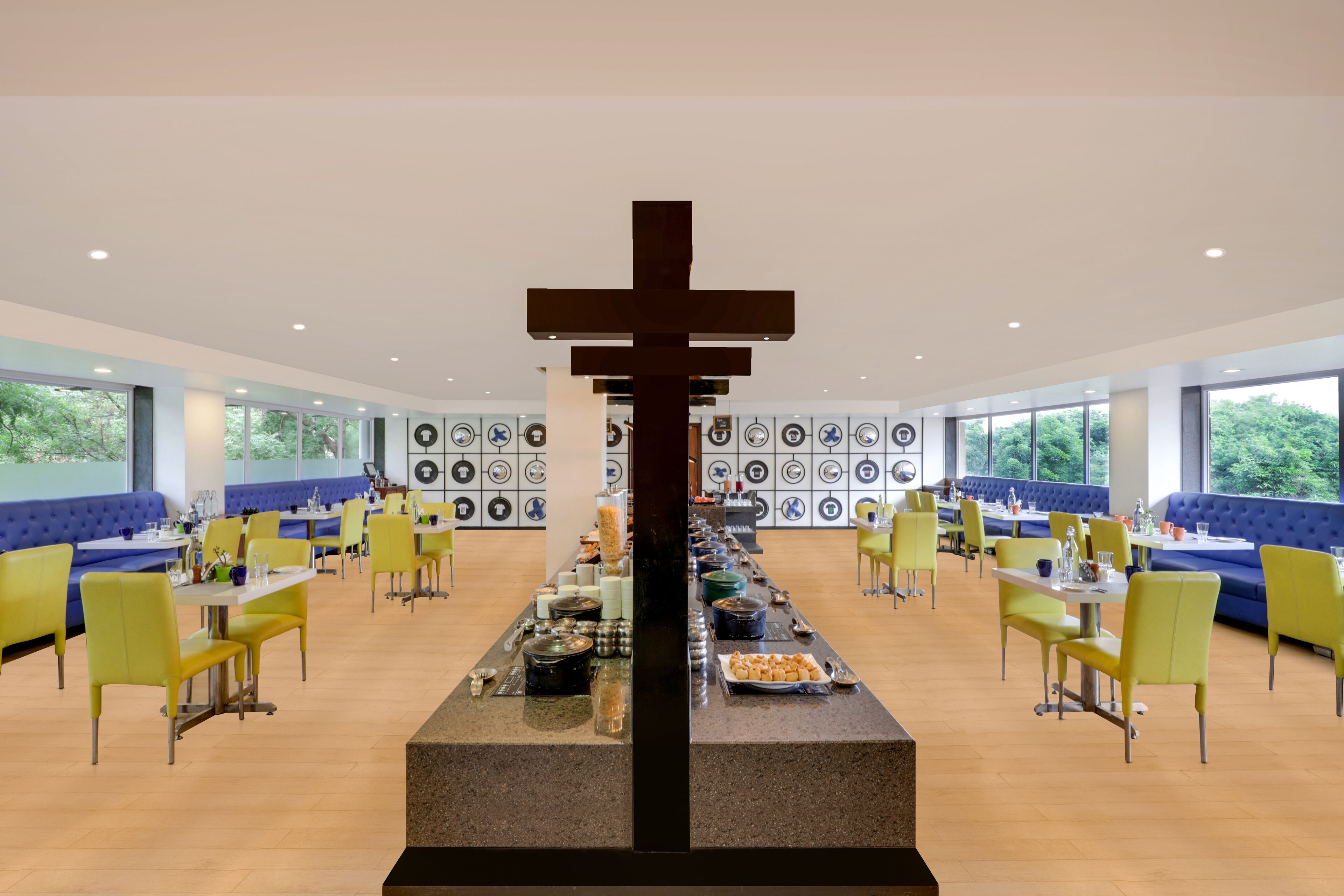 A modern dining area with yellow chairs, blue booths, and a central decorative structure.