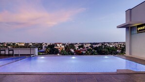 A rooftop infinity pool with a city view, a bar area, and a sign indicating a pool area. - Lemon Tree Hotel Hubli (Hubli)