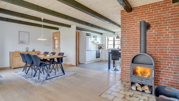 Un interior moderno con comedor, cocina y estufa de leña.