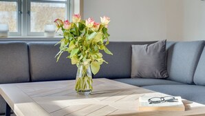 Una habitación con un sofá gris, una mesa de centro de madera y un jarrón con flores.
