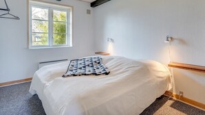 Un dormitorio con cama, ventana, lámpara colgante y una lámpara de pared.