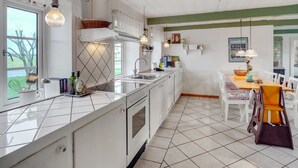 Eine Küche mit einer zentralen Kochinsel, weißen Schränken, einem Backofen, einer Spüle und einem Essbereich mit Tisch und Stühlen.