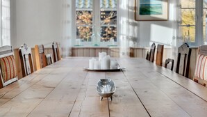 Ein langer Holztisch mit Stühlen, eine Serviertablett mit weißen Tassen und eine dekorative Schale in der Mitte.