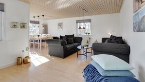 A modern living room with two sofas, a dining area, and a kitchen in the background.