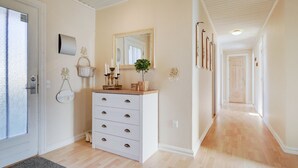 A hallway with a white dresser, a mirror, and a plant.