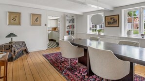 Un comedor con una mesa larga, sillas, un tapete estampado y vistas al exterior.