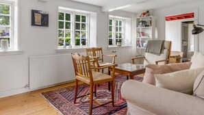 Una habitación luminosa con paredes blancas, muebles de madera y ventanas amplias.