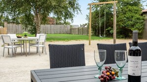 Un patio al aire libre con una mesa lista para comer, rodeado de sillas de mimbre.