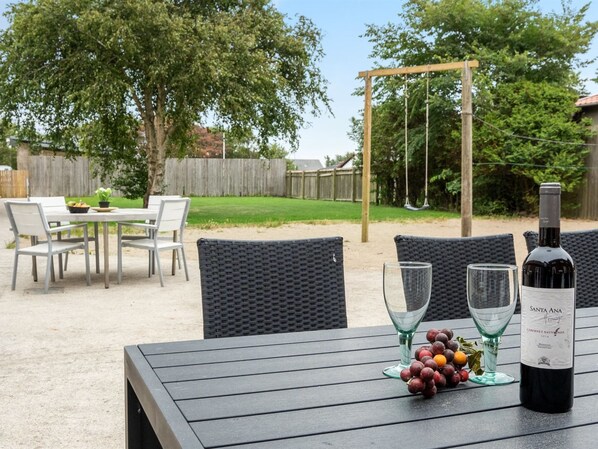 An outdoor patio with a table set for dining, surrounded by wicker chairs.