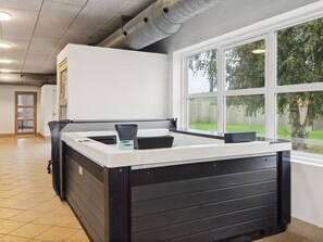 A kitchen with a large island, a window with a view of a backyard, and a door leading to another room. - Vacation home "Saga" by Interhome (Bredebro)