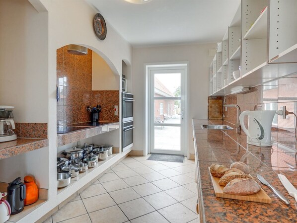 A modern kitchen with granite countertops, stainless steel appliances, and a view of the backyard through an open door.