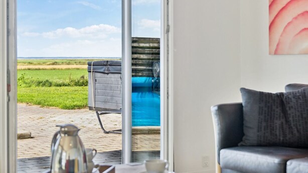 A room with a view of a green field and a blue swimming pool.