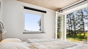 A bedroom with a bed, a window, and a view of trees.