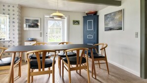 A dining area with a wooden table and chairs, a blue cabinet, and a painting on the wall. - "Ingulf" - 18km from the sea by Interhome (Bredebro)