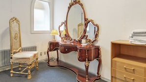 Ein Zimmer mit Schminktisch, Stuhl, Kommode und Fenster.
