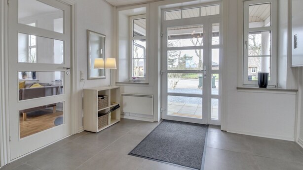 A bright, well-lit entryway with a glass door leading to a patio. There is a small shelf with a lamp and a mirror above it. - "Juuso" - 20km from the sea by Interhome (Bredebro)