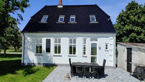 A white house with a tiled roof, a patio with a table and chairs, and a small attached structure. - "Juuso" - 20km from the sea by Interhome (Bredebro)