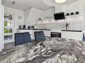 A modern kitchen with white cabinets, a flat-screen TV, and a dining area with a marble table. - "Juuso" - 20km from the sea by Interhome (Bredebro)