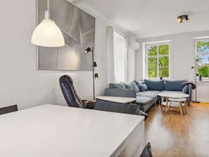 Un salon moderne avec un canapé, une table à manger et une grande fenêtre.
