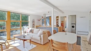 Un salon moderne avec un canapé, une table à manger et des chaises. On aperçoit également un coin cuisine avec un lave-linge.