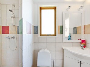 Un baño con ducha, inodoro, lavamanos y ventana.