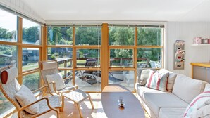 Un salon spacieux avec de grandes fenêtres, un canapé, des fauteuils et une table basse.