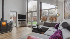 A modern living room with a fireplace, large windows, and a cozy sofa. - "Holmwith" - 200m from the sea by Interhome (Aabenraa)