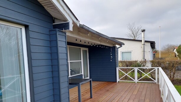 Ett blått hus med en träveranda och vita räcken.