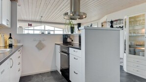 Eine moderne Küche mit weißen Schränken, einer Edelstahl-Dunstabzugshaube und einem eingebauten Geschirrspüler.
