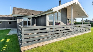 A modern house with a covered patio, a fenced yard, and a clear blue sky.