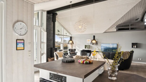 A modern kitchen with a central island, built-in oven, and a dining area with a sofa and chairs.