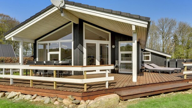 Een modern huis met een terras, grote ramen en een schotelantenne.