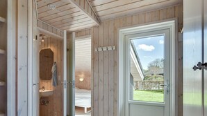 Een houten interieur met een badkamer, een slaapkamer en een deur die naar een tuin leidt.