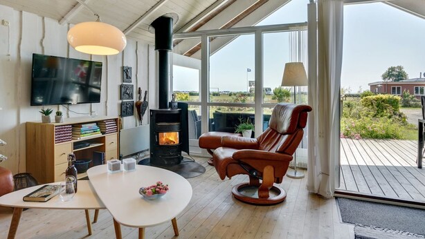 Ein gemütliches Wohnzimmer mit Kamin, Fernseher und bequemem Sessel.