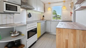 A modern kitchen with white cabinets, a microwave, a stove, and a wooden island.