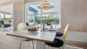 A dining area with a table set for two, a bench, and a view of the outside.