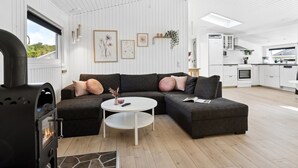 A modern living room with a sectional sofa, a small white table, and a wood-burning stove. - "Fiete" - 200m from the sea by Interhome (Bjert)