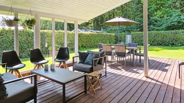 A covered outdoor patio with wooden flooring, seating arrangements, and a table with chairs. - "Fiete" - 200m from the sea by Interhome (Bjert)