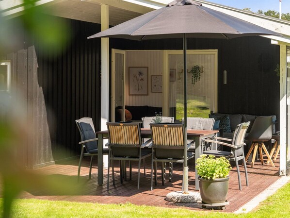 An outdoor patio with a table and chairs, a potted plant, and a covered seating area. - "Fiete" - 200m from the sea by Interhome (Bjert)
