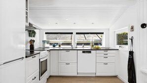 A modern kitchen with white cabinetry, a built-in oven, and a large window providing natural light. - "Fiete" - 200m from the sea by Interhome (Bjert)