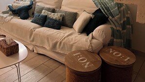 A cozy living room with a sofa, pillows, a lamp, and a staircase.