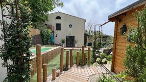 A wooden deck with a pool, surrounded by a wooden fence and greenery.