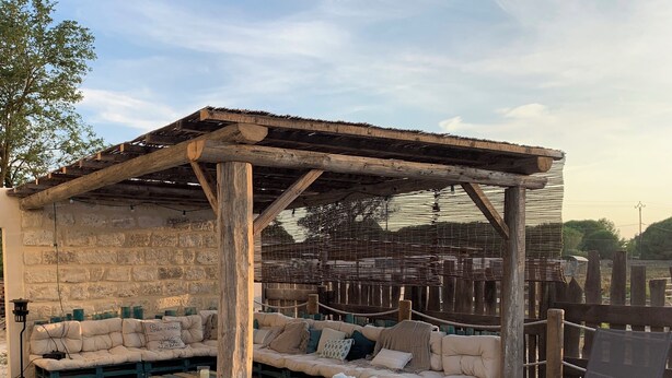 A wooden deck with a covered seating area, stone walls, and a rustic wooden fence.